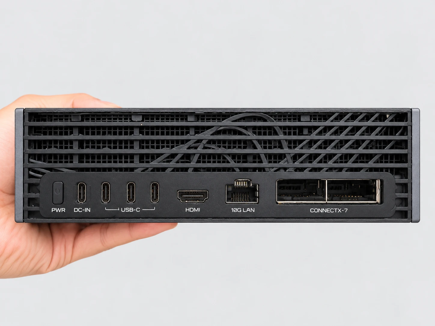 手に持ったAI TOP ATOMの背面:PWRボタン、USB-CのDC-IN入力、USB-Cポート三つ、HDMI出力、10G LANポート、ConnectX-7カードのQSFPポート二つ。